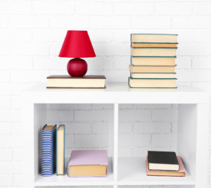 Wooden shelf with books and lamp on brick wall background